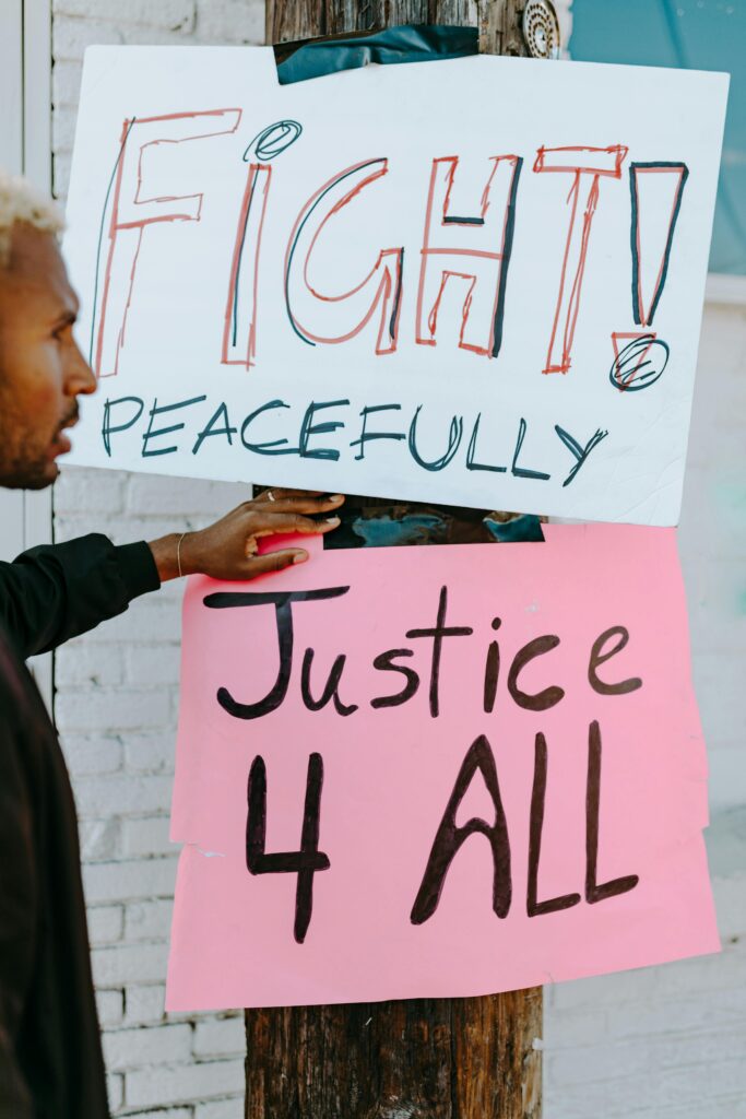 Close-up of a peaceful protest sign reading 'Fight Peacefully, Justice 4 All'.